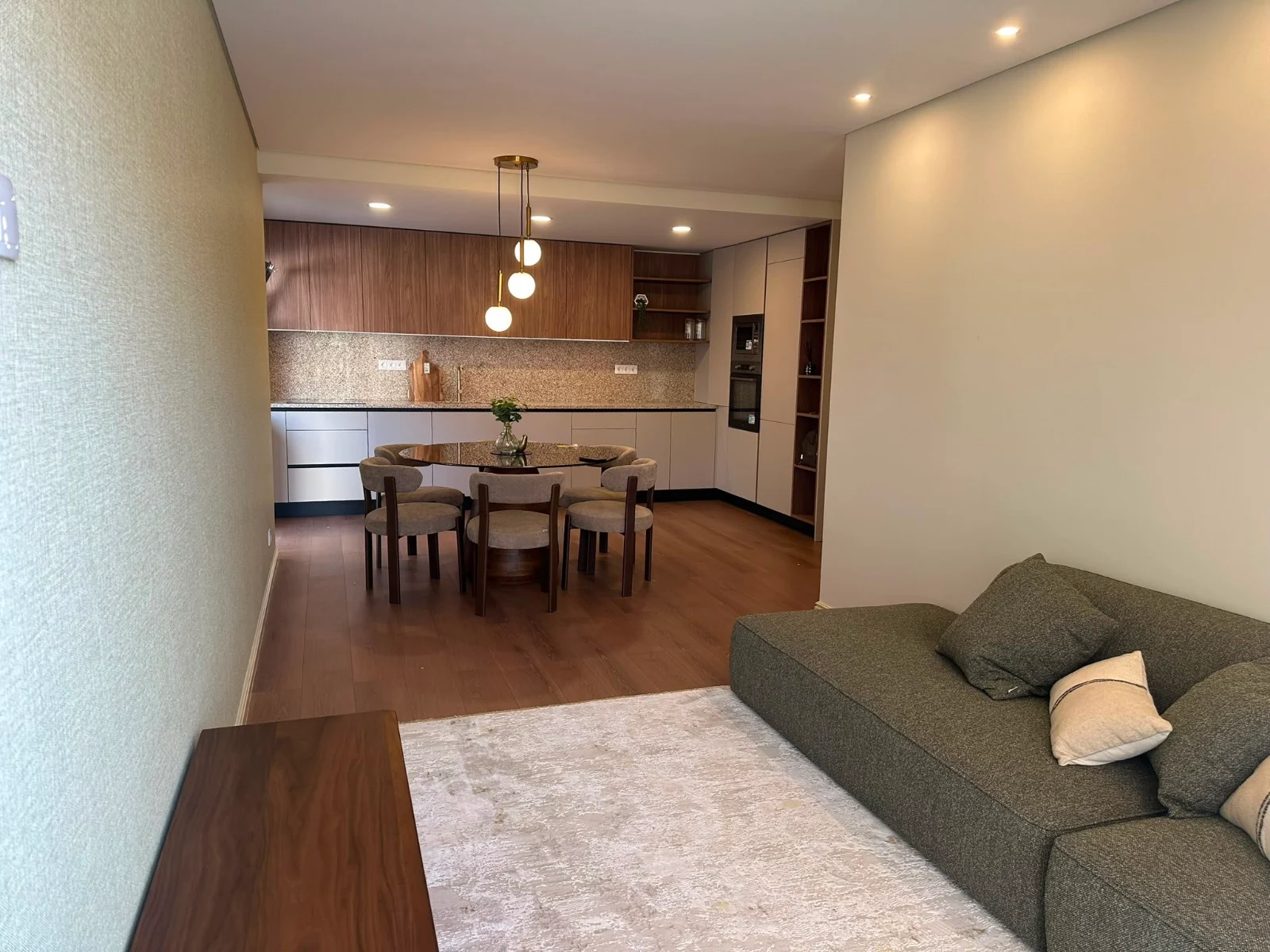 Sala depois da transformação: cozinha aberta, pavimento em madeira e iluminação embutida